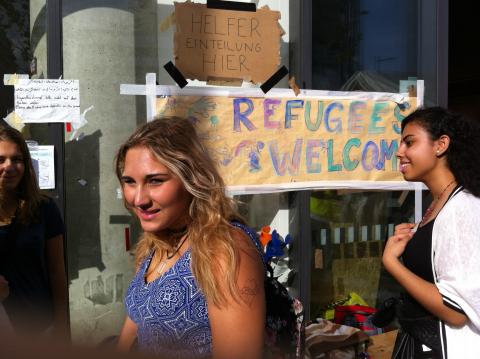 Schülerin am Bahnhof vor Plakat "Refugees welcome"